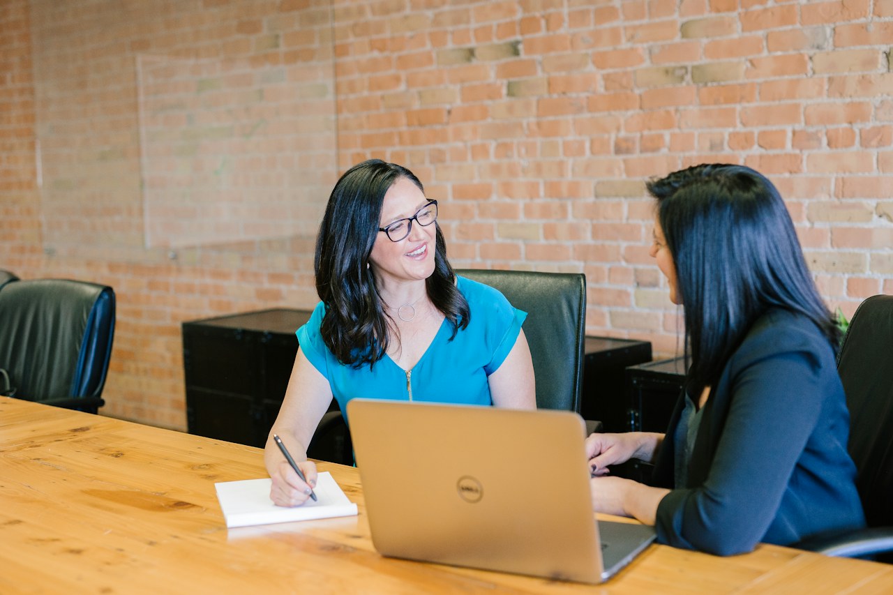Two professionals discussing plans at a table with a laptop