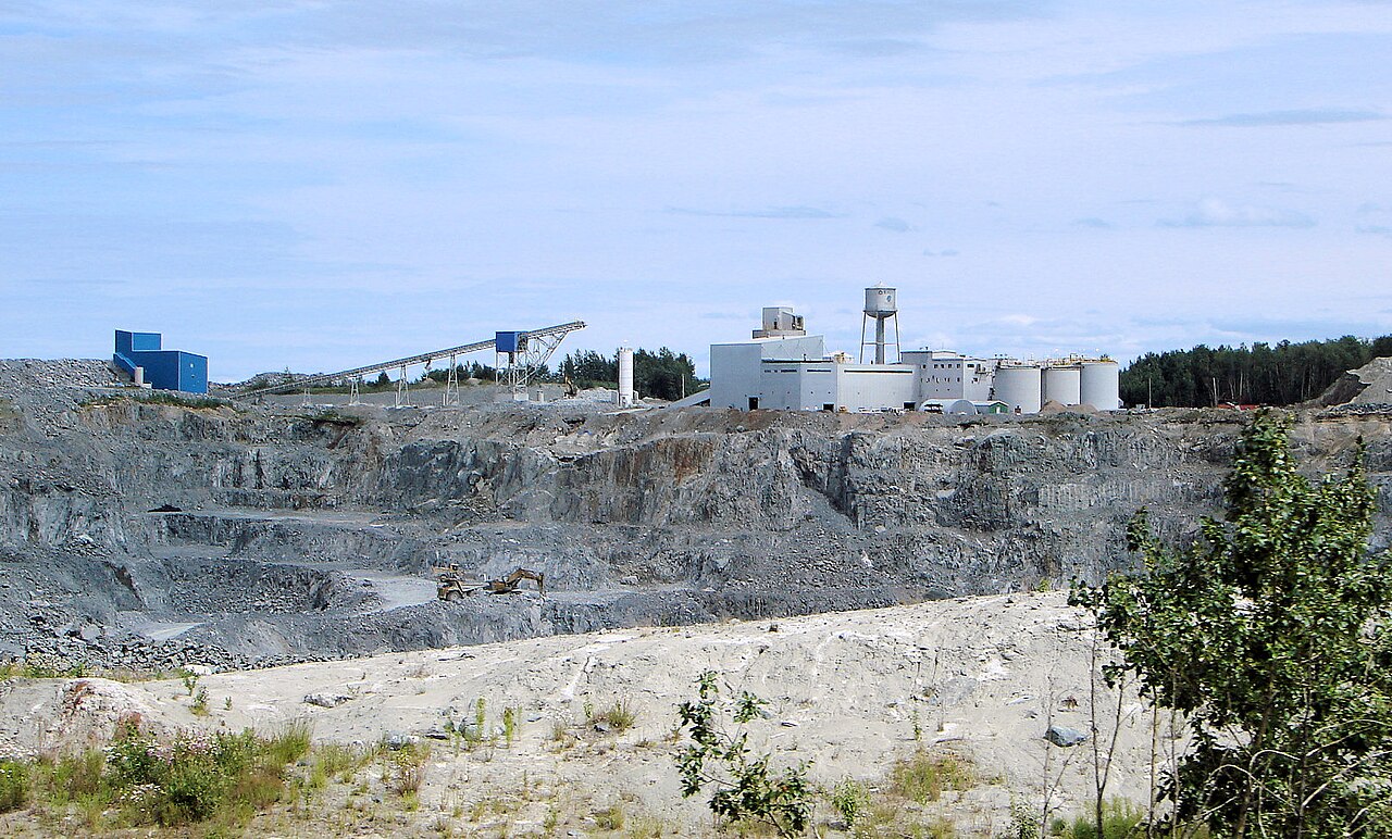 Open-pit mine with terraced rock benches and processing infrastructure